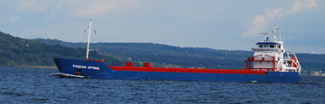 A freighter and barge pass closely each other.