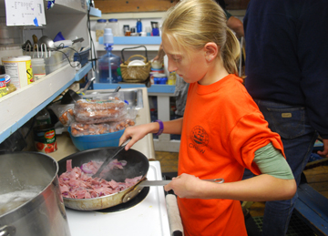 Emily cooks ham in the galley.