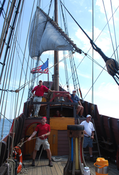 The lateen catches the wind over the Quarter deck crew's heads.