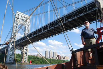 Bob Hansen stands at the com as the ship passes under the George Washington Bridge.