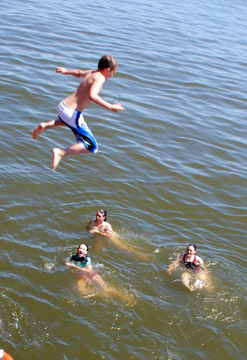 Nick pounces in mid-air above swimming Nora, Sanne, and Rachel.