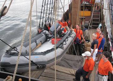 The crew uses tackles to heave the Zodiac over the rail.