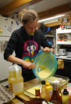 Jeanine pours cake batter from a bowl into a pan.