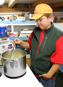 Colton stirs a pot of soup.